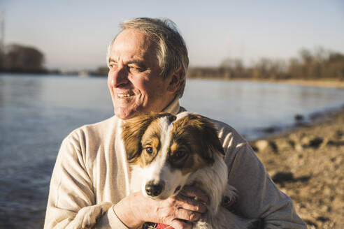 Glücklicher Mann mit Hund an einem sonnigen Tag - UUF25611