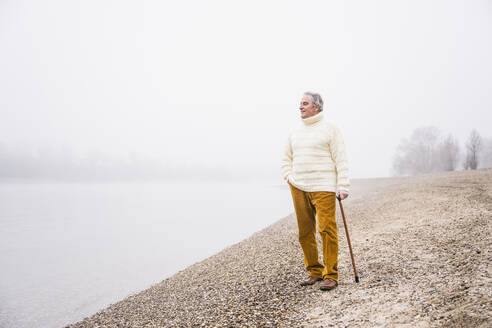 Mann mit Gehstock stehend mit Hand in der Tasche am Strand - UUF25621