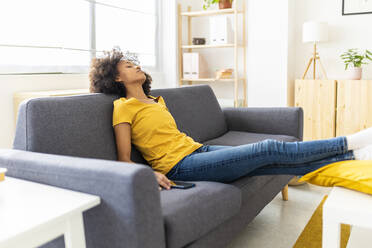 Junge Frau schläft auf dem Sofa im Wohnzimmer zu Hause - XLGF02692