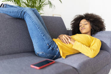 Young woman sleeping on sofa in living room at home - XLGF02710