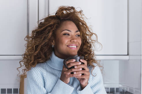 Lächelnde Frau mit Kaffeetasse zu Hause - PNAF03098