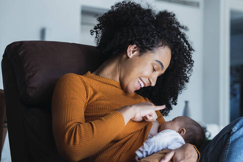 Smiling mother breastfeeding son in living room - PNAF03170