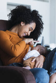 Mutter stillt kleinen Jungen im Wohnzimmer zu Hause - PNAF03171