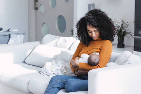 Mother breastfeeding and looking at son in living room - PNAF03174