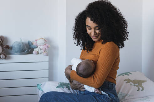 Mother breastfeeding baby boy in bedroom - PNAF03175