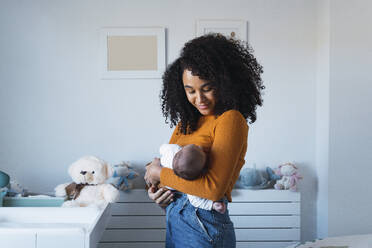 Mother standing and carrying baby boy in bedroom - PNAF03215