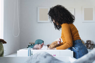 Mother keeping baby boy in crib at home - PNAF03218