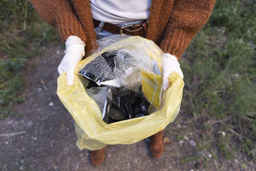 Woman standing with garbage bag full of plastic at forest - JPTF01062