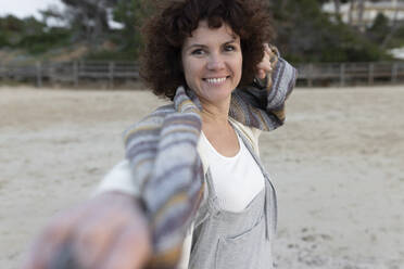 Smiling woman standing on sand at beach - JPTF01071