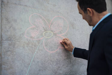 Geschäftsmann mit Kreidezeichnung Blume an der Wand - MOEF04009