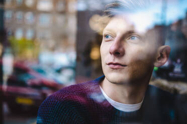 Contemplative young man seen through glass window - AMWF00177