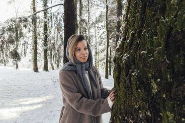 Glückliche Frau steht an einem Baum im Wald - OMIF00634