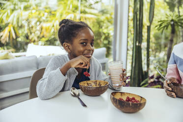 Smiling girl having berries at table in dining room - MFF08403