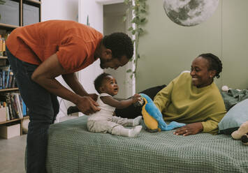 Father and mother playing with son in bedroom at home - MFF08437