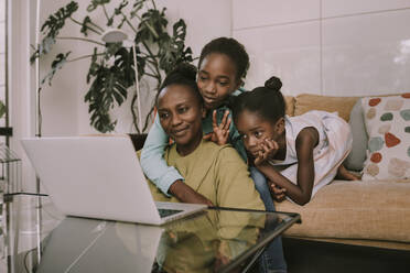 Mother and children on video call through laptop in living room - MFF08456