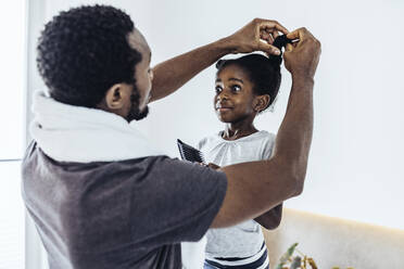 Vater bindet die Haare seiner Tochter im Badezimmer zu Hause zusammen - MFF08474