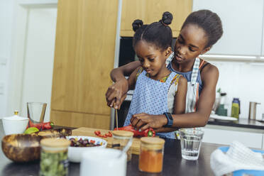 Siblings cutting vegetables together in kitchen - MFF08488