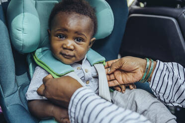Mother checking buckles in car seat of baby boy - MFF08511