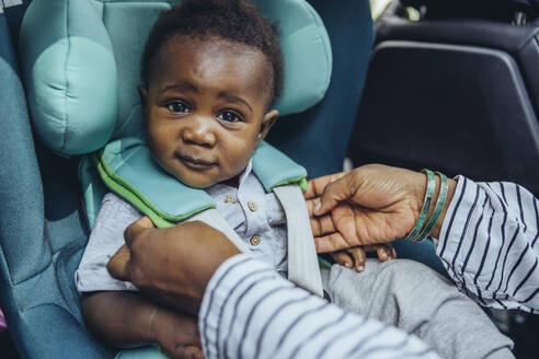 Mutter prüft Schnallen im Autositz eines kleinen Jungen - MFF08511