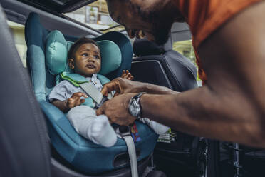 Father fastening seat belt of son in car - MFF08514