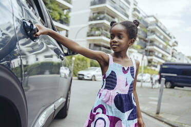 Mädchen öffnet Autotür auf der Straße stehend - MFF08539