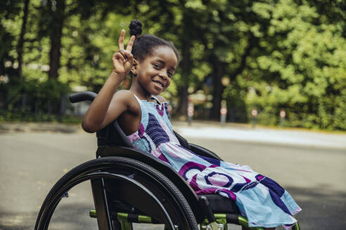 Disabled girl in wheelchair making peace sign - MFF08547