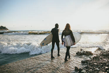 Surfer im Neoprenanzug mit Surfbrett am Strand - OMIF00653