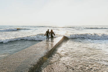 Surfer mit Surfbrett auf einem Betonsteg - OMIF00655