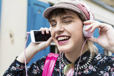 Happy young woman listening to music through headphones - WPEF05816