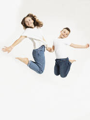 Fröhlicher Bruder und Schwester springen vor weißem Hintergrund - SDAHF01120