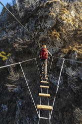 Abenteuerlustiger Rucksacktourist überquert tibetische Brücke, Orobie-Alpen, Bergamo, Italien - MCVF00954