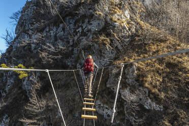 Wanderer beim Überqueren einer Hängebrücke in den Orobie-Alpen, Bergamo, Italien - MCVF00955
