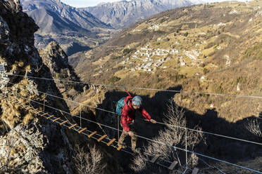 Abenteuerlustiger Mann überquert tibetische Brücke, Orobie-Alpen, Bergamo, Italien - MCVF00957