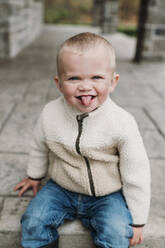 Cute boy sticking out tongue on porch - ELEF00057