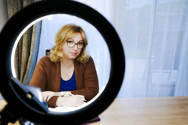 Frau mit Stift und Buch vor Ringlicht zu Hause - IHF00749