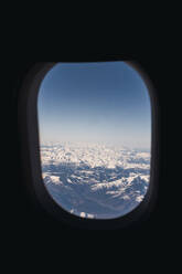 Schneebedeckte Berge durch ein Flugzeugfenster gesehen - PNAF03255