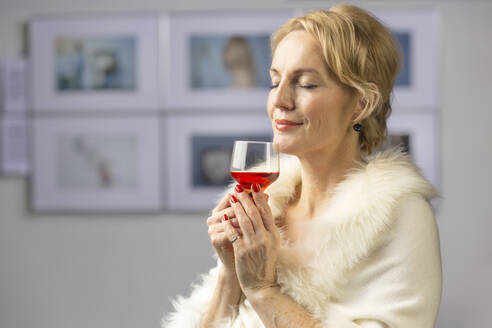 Lächelnde Frau mit Weinglas bei der Eröffnungsfeier einer Ausstellung - VGF00419