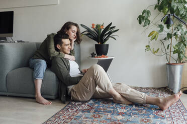 Junges Paar teilt sich einen Laptop im heimischen Wohnzimmer - VPIF05356