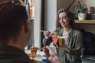 Lächelnde Frau isst chinesisches Essen mit ihrem Freund zu Hause - VPIF05377