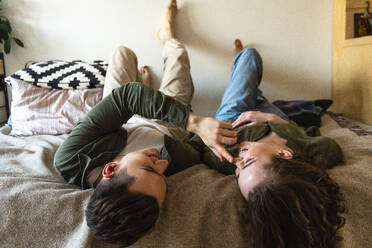 Happy man touching girlfriend's nose lying on bed at home - VPIF05406