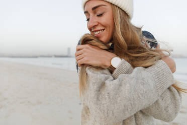 Happy woman with eyes closed hugging self at beach - TYF00079