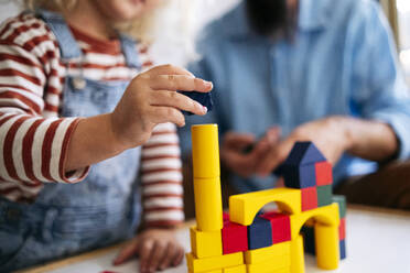 Boy building house with toy blocks by father at home - ASGF02126