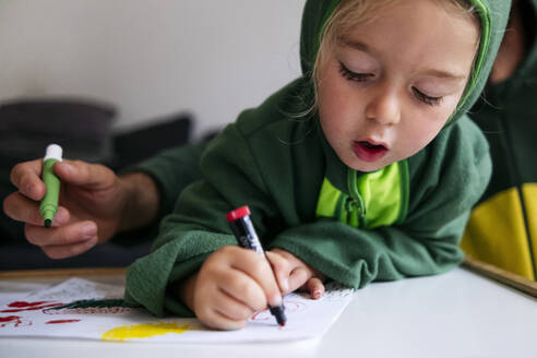 Cute boy drawing on paper over table at home - ASGF02133