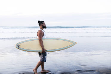 Bärtiger Mann mit Surfbrett am Strand - ASGF02159