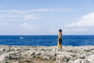 Tourist steht auf einem Felsen und betrachtet das Meer, Menorca, Spanien - DGOF02279