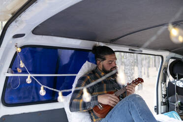 Bärtiger Mann spielt Gitarre im Van sitzend - ASGF02172