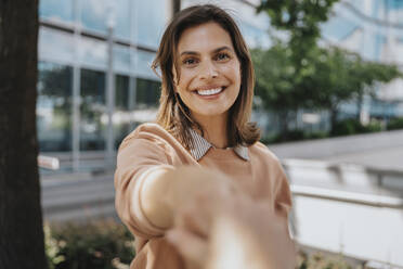 Happy woman shaking hands at office park - MFF08561