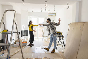 Young couple renovating home and dancing in living room - EIF03304