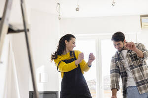 Happy young couple dancing in living room - EIF03306