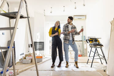 Fröhliches Paar renoviert sein Haus und tanzt im Wohnzimmer - EIF03307